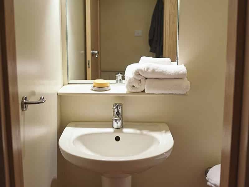 A holiday let bathroom with fresh folded towels on the shelf